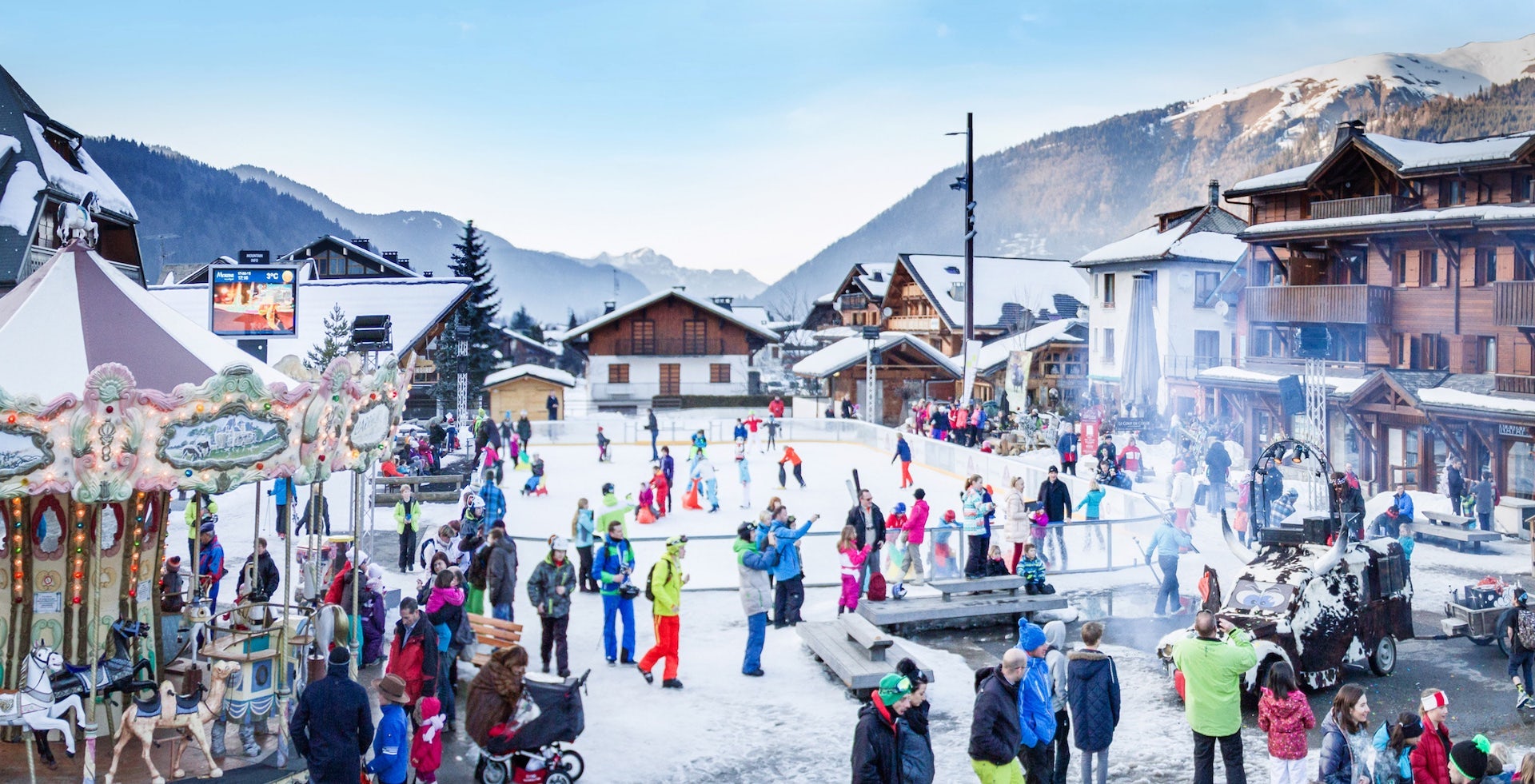Families in a snowy square with an ice rink in the centre of the family friendly resort of Morzine in winter.